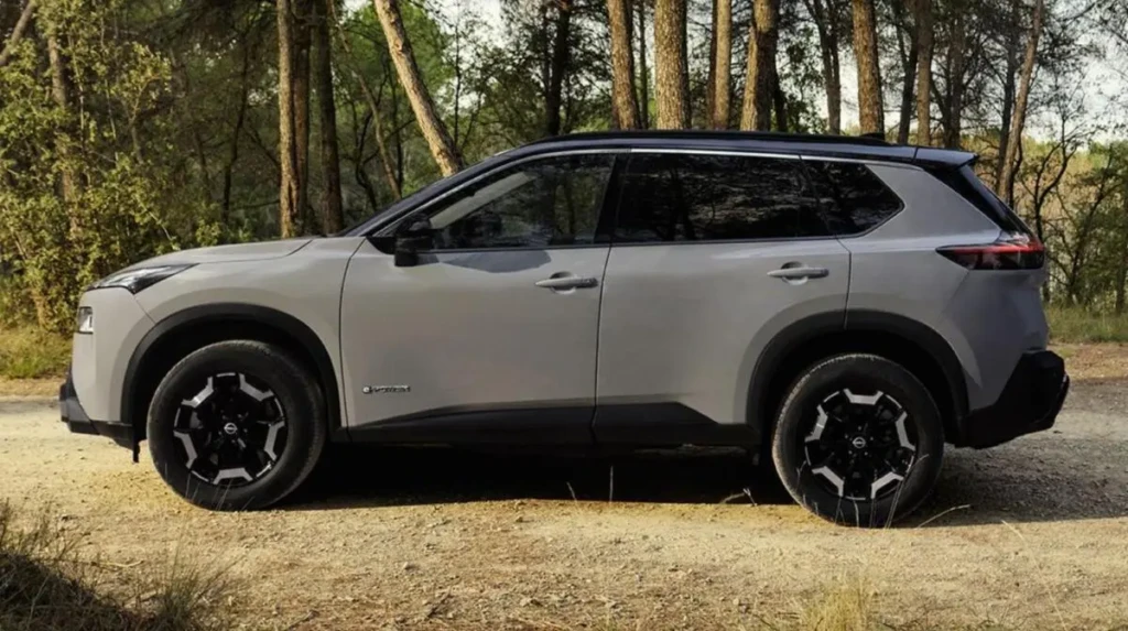 Кросовер Nissan X-Trail 2026 у профіль на ґрунтовій дорозі серед дерев