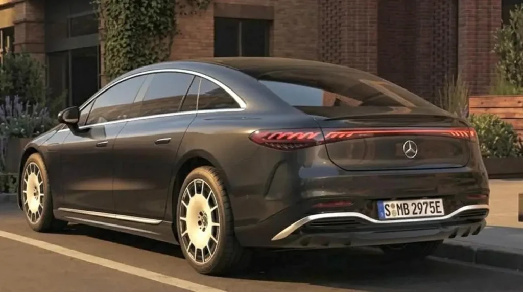 Новий Mercedes EQS темного кольору в русі міською вулицею, вид спереду збоку