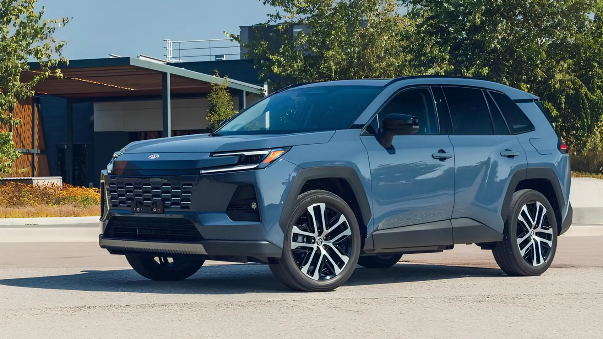 Синьо-сірий кросовер Toyota на дорозі біля сучасної будівлі