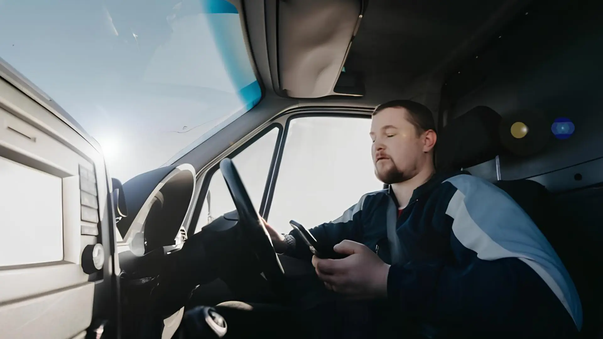 Водій у салоні автомобіля користується смартфоном під час поїздки