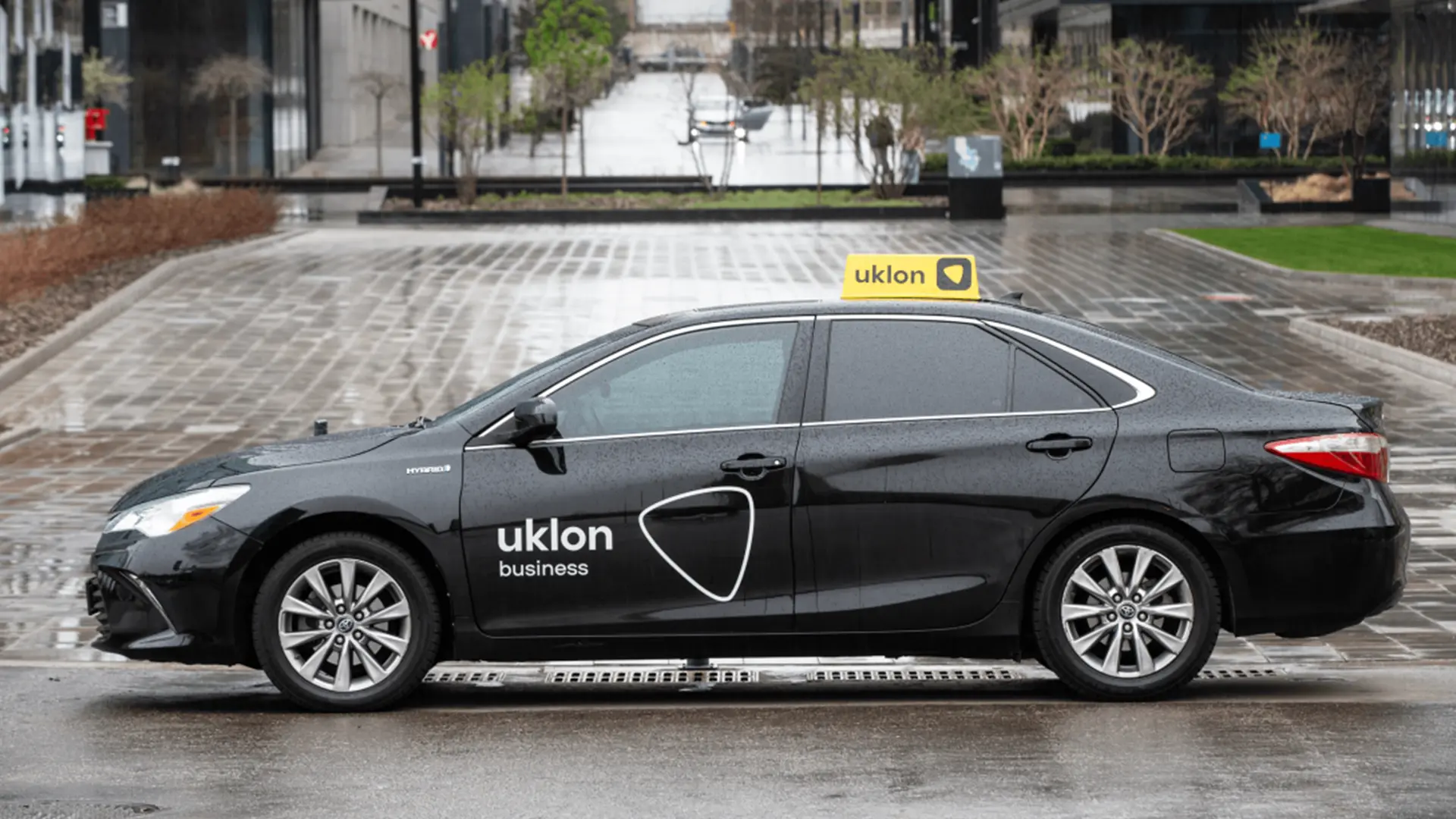 Чорний автомобіль Uklon business на мокрій міській дорозі