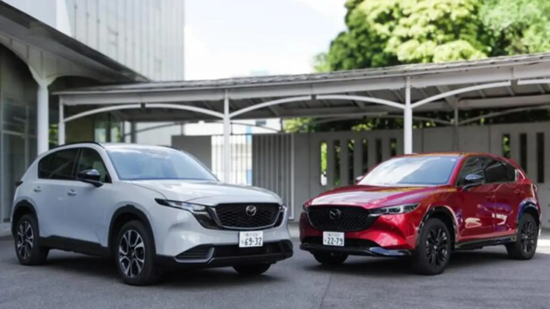 Білий і червоний кросовери Mazda CX-5 біля сучасної будівлі