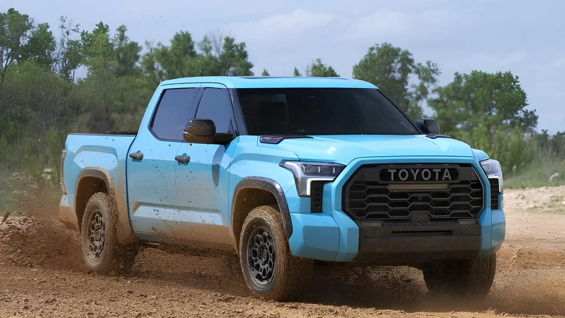 Блакитний Toyota пікап їде бездоріжжям у хмарі пилу