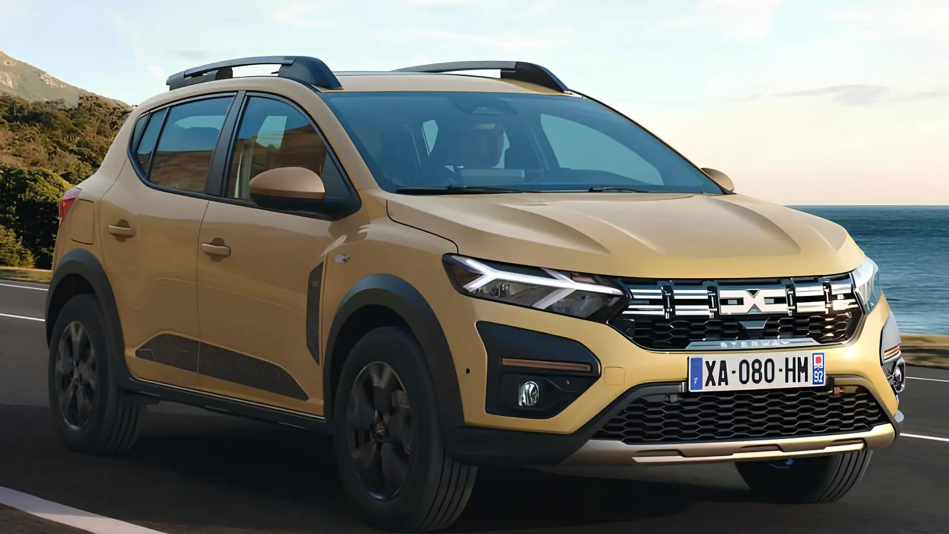 Жовтий Dacia Sandero Stepway їде дорогою біля моря