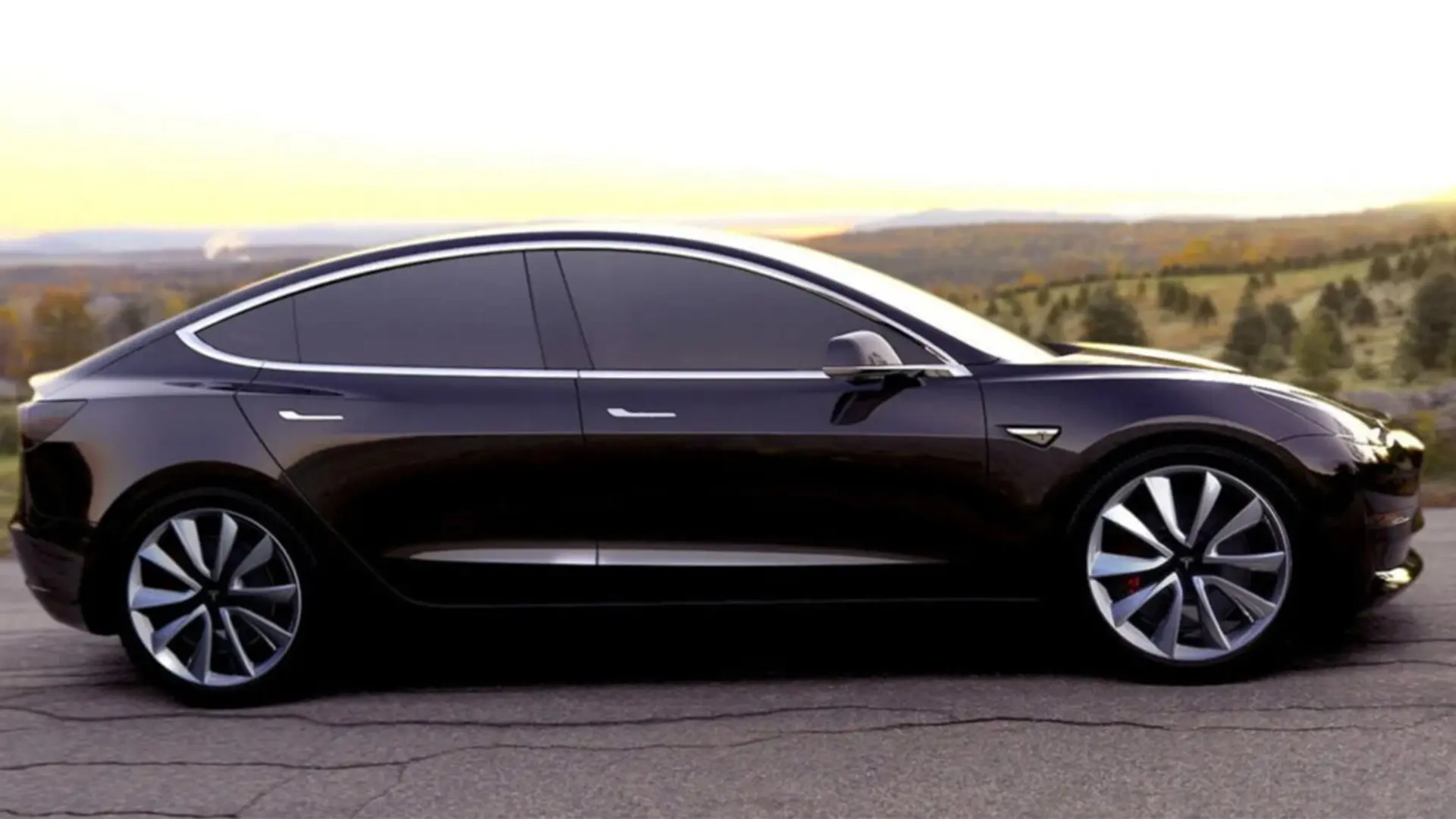 Чорний електромобіль Tesla на дорозі на тлі заміського пейзажу