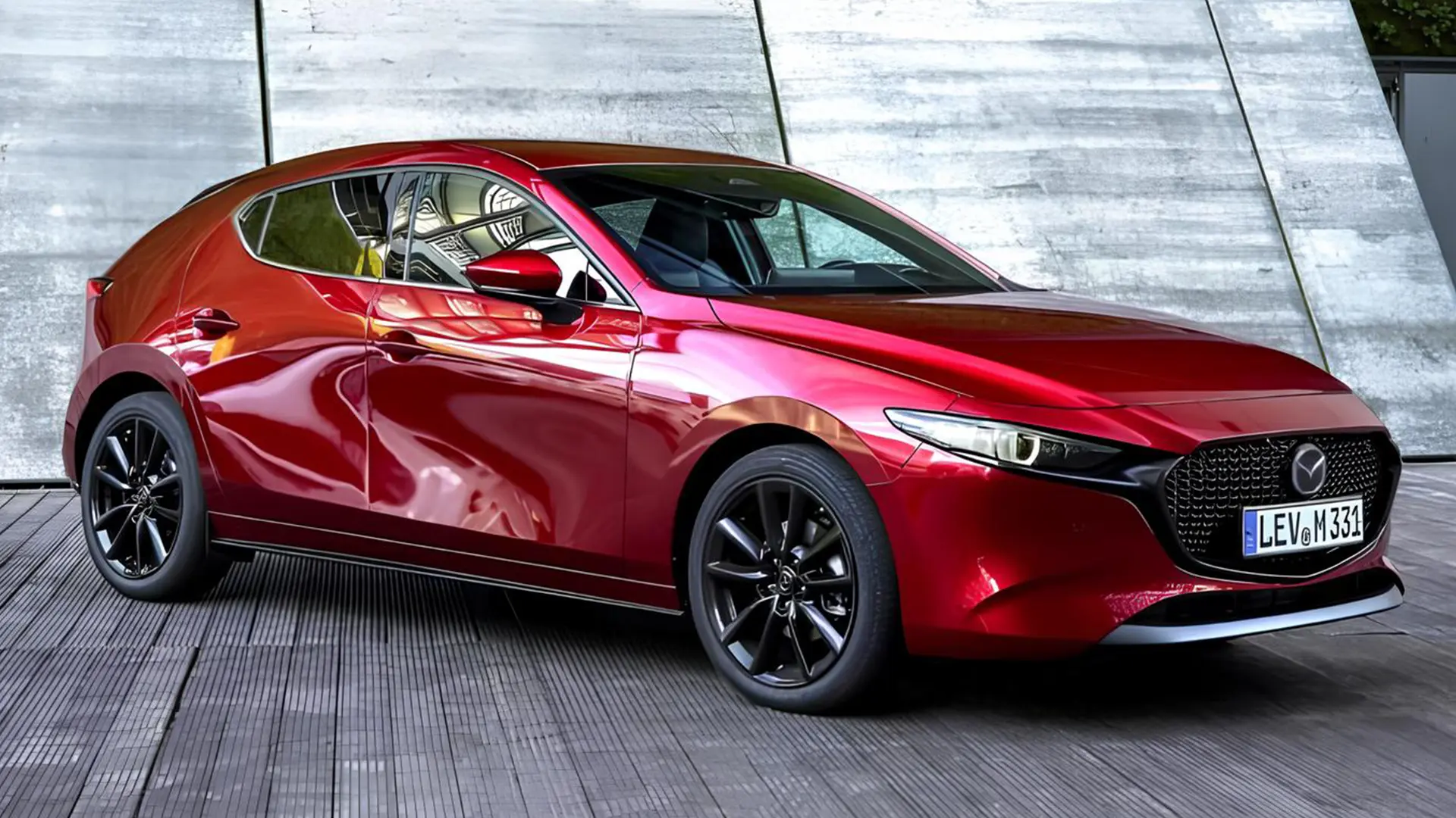 Червона Mazda 3 2027 біля сучасної бетонної будівлі