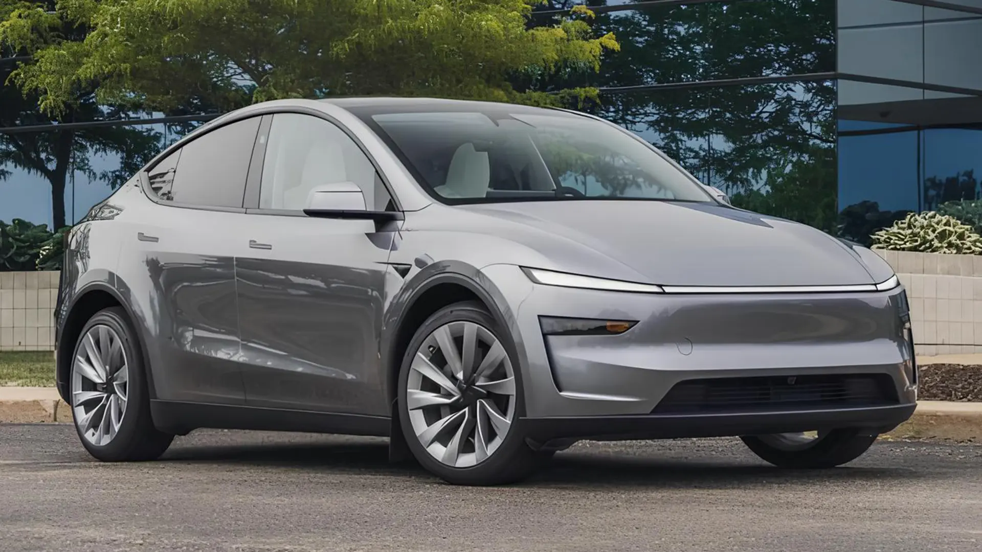Сіра Tesla Model Y 2026 біля сучасної будівлі