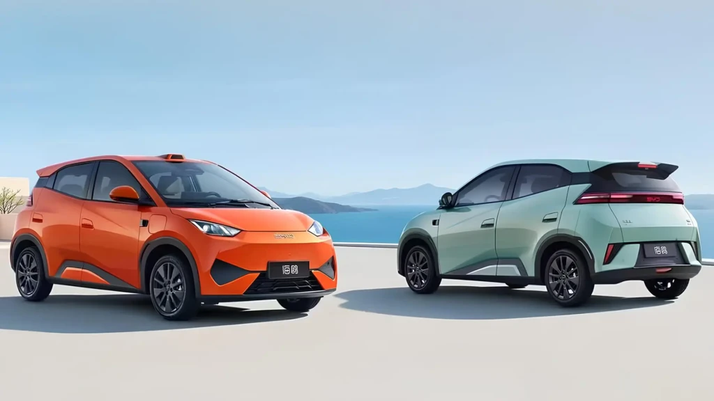Два автомобілі BYD Dolphin Surf у помаранчевому та світло-зеленому кольорах на терасі біля моря