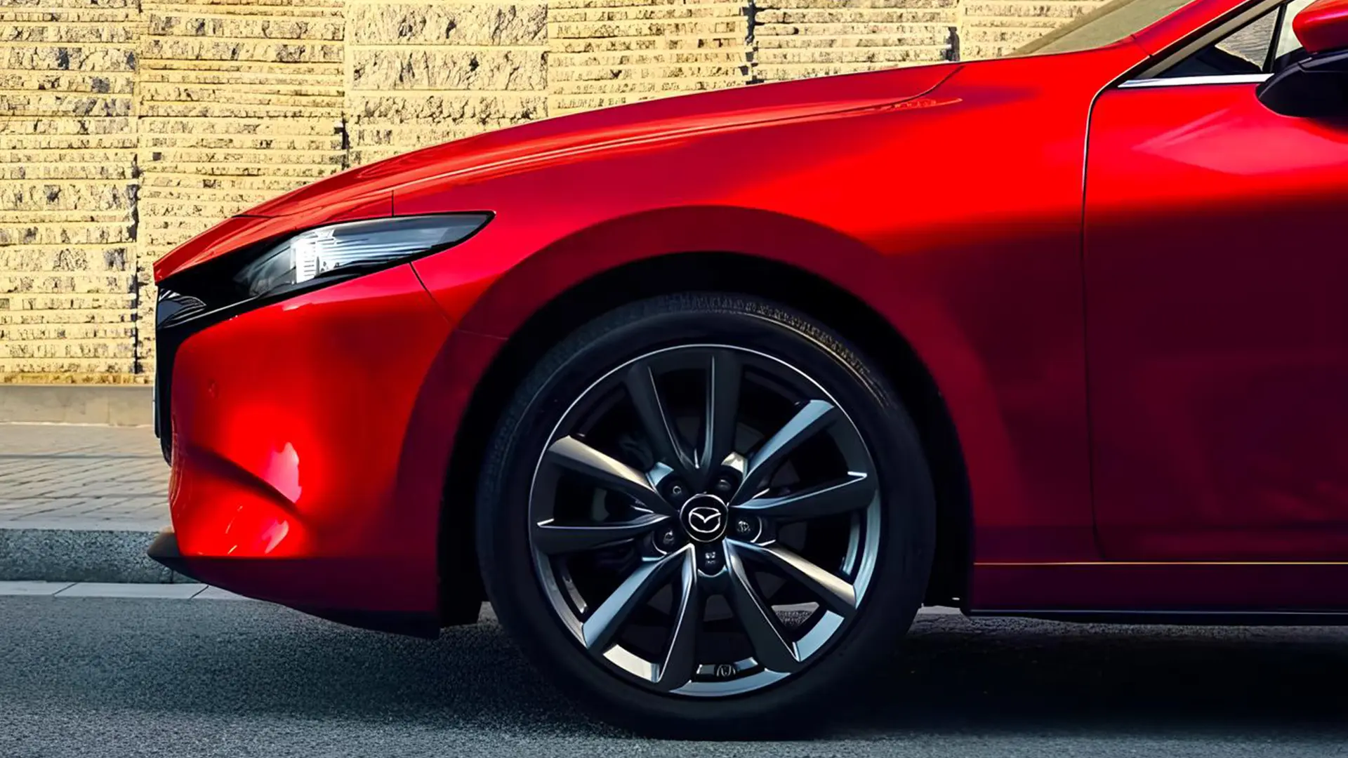 Передня частина червоного автомобіля Mazda з крупним планом колеса