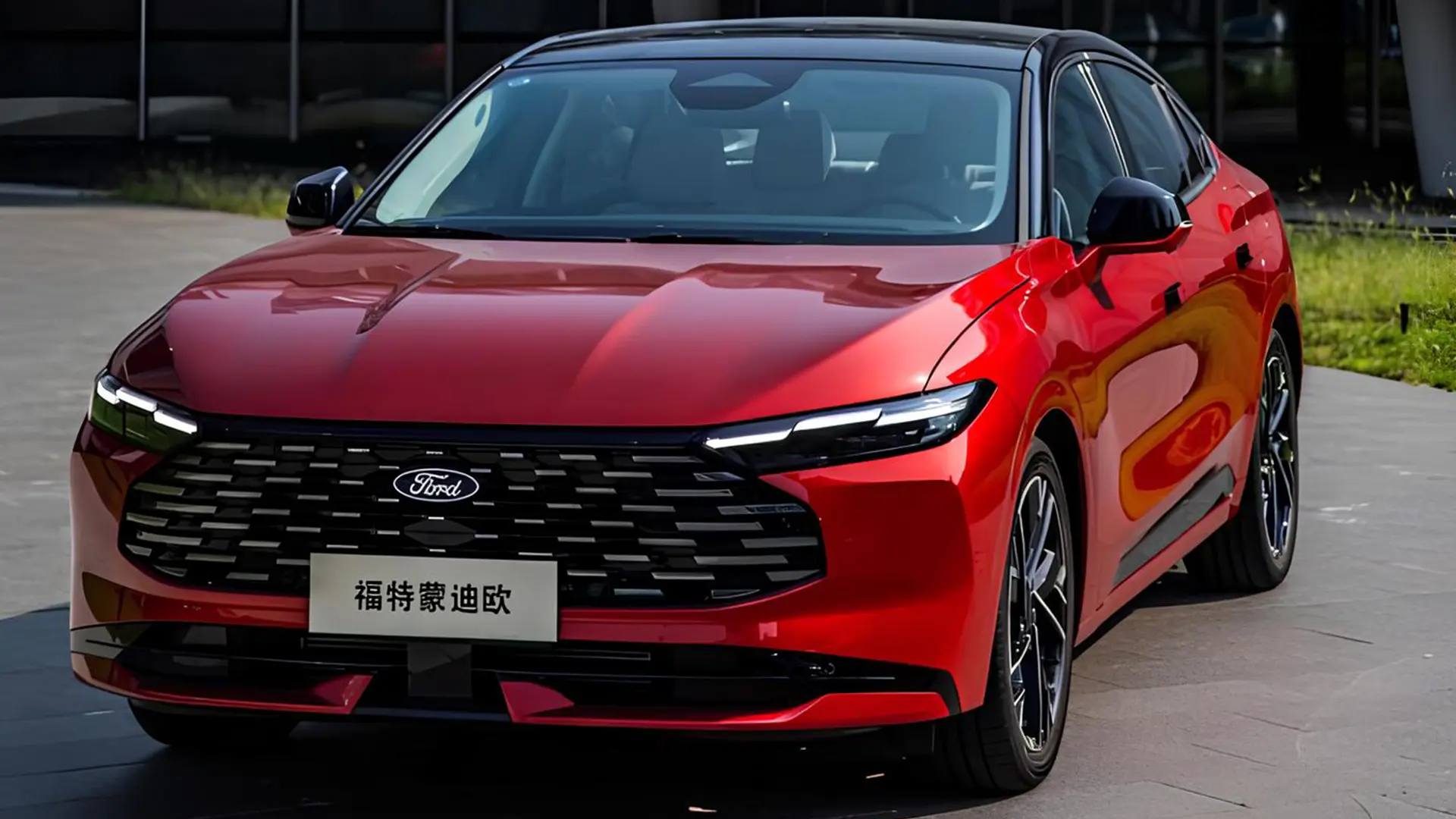 Червоний седан Ford на майданчику біля сучасної будівлі, вигляд спереду збоку