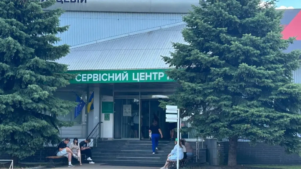 Вхід до сервісного центру МВС з українським прапором і людьми біля сходів